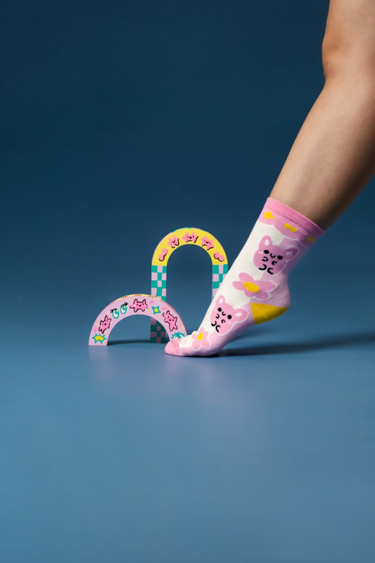 A model's foot wearing pink and white socks posing in front of arch props made by Malaysian artist QuirkyQing